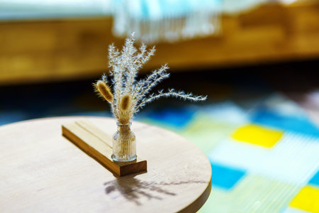 Decorative bouquet of dry grass in a simple glass vase on the tableの写真素材