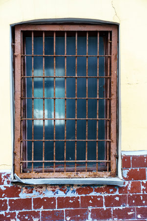 Old window with dirty glass and rough metal grilleの写真素材