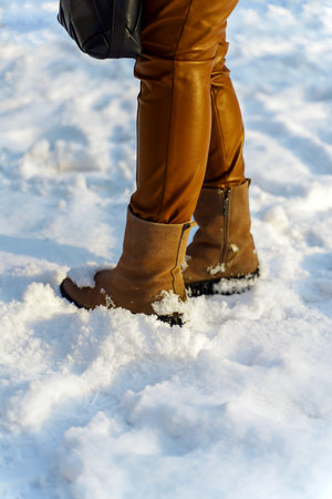 Women's feet in leather pants and yellow suede boots in the snowの写真素材