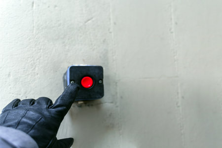 A finger in a black leather glove is brought over the red button