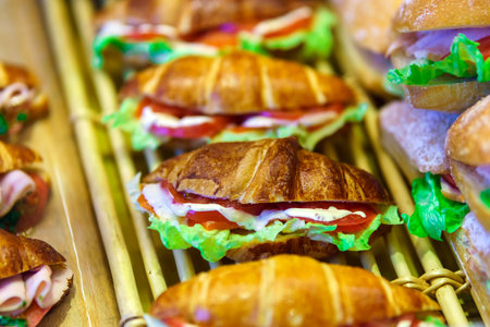 Croissant with salmon, tomatoes, herbs and sauce on the counter for sale