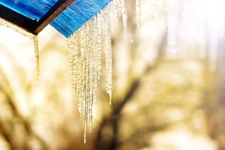 Icicles with drops of the bottom on the roof of blue color in the springの写真素材