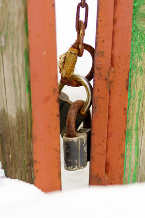 Old padlocks hang on a chain on the fence