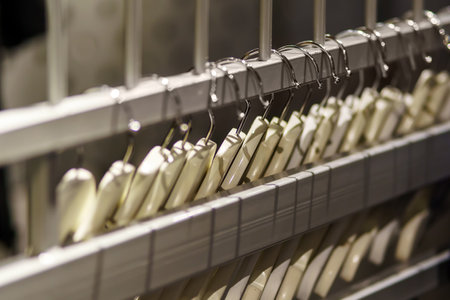 A row of hangers for clothing made of wood on metal grilleの写真素材