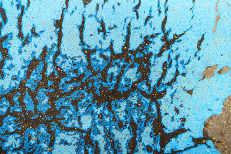 Blue cracked paint on black wet asphalt on a cloudy dayの写真素材