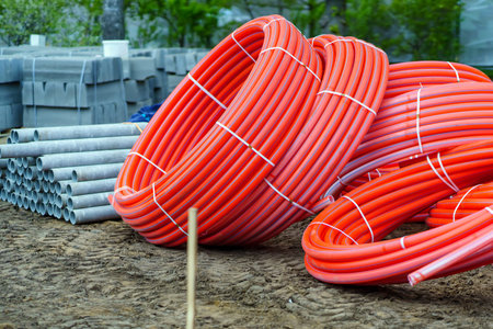 Red plastic pipes rolled into rings and other building materialsの写真素材