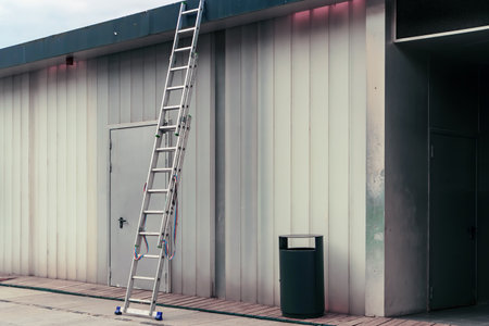 A sliding staircase made of aluminum is placed to access the roof of the buildingの写真素材