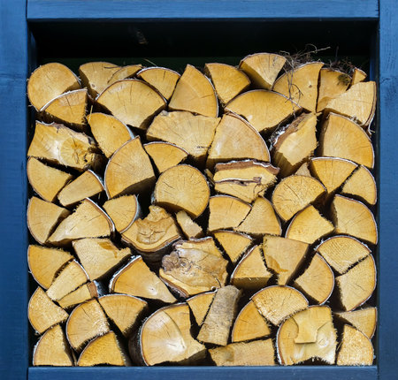 Chopped firewood is neatly stacked in a square niche of blue colorの写真素材