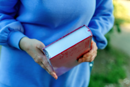 The girl holds in her hands a new book of red color in polyethyleneの写真素材