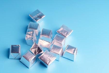 Square candies in a silver wrapper lying on a blue background