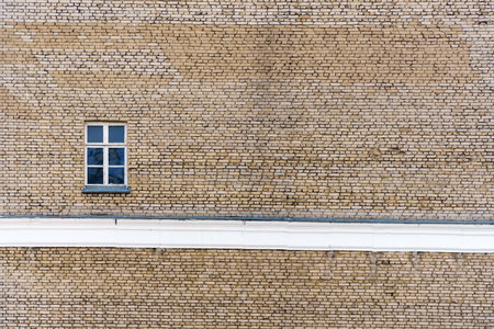 A lonely window on a large brick wall