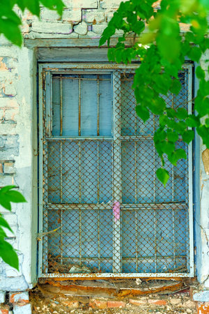 An old window with a lattice and a chain-link mesh