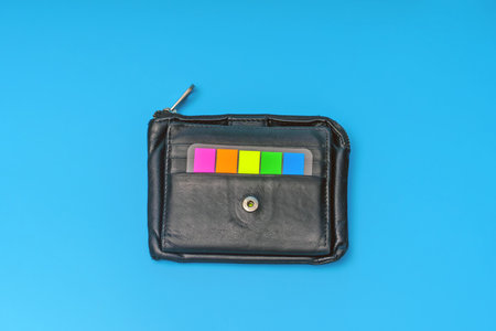 Black leather wallet with colored stickers on a blue backgroundの写真素材