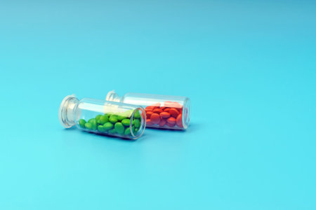 Two glass jars with medicines of green and red color lie on a blue background