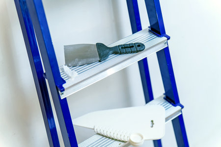 A metal spatula rests on a stepladder during repairsの写真素材