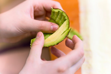 Child's hands peeling avocado for healthy foodの写真素材