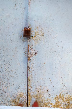 The padlock on the metal door is covered with a plastic bottleの写真素材