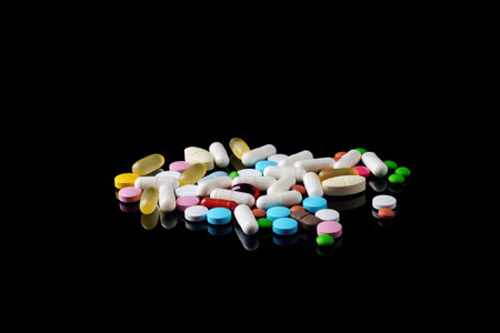 Different multicolored pills on black background with reflection