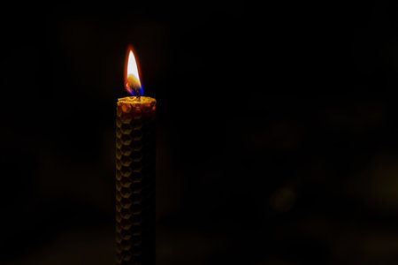 Honeycomb texture candle burning on dark backgroundの写真素材