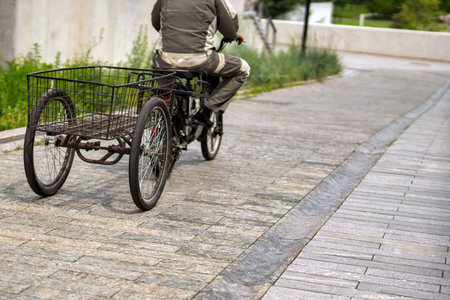 worker pedals a tricycle with a large rear cargo basket, a blend of utility and sustainable...