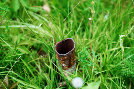 piece of metal pipe with a sharp edge sticks out of the grass