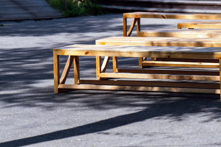 serene park, simple wooden benches face a stage on a paved area, inviting relaxation and community...