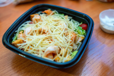 vibrant shrimp salad in a sleek plastic dish, showcasing fresh greens, succulent shrimp, and a...