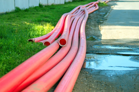 vivid red polyethylene pipes, severed and sprawled over the earth, juxtapose industrial utility with the artistry of discarded materials, symbolizing the intersection of function and decayの写真素材