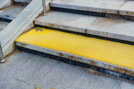 vibrant yellow rubber anti-slip surface enhances the safety of stone steps, merging functionality with aesthetic appeal in an urban environmentの写真素材