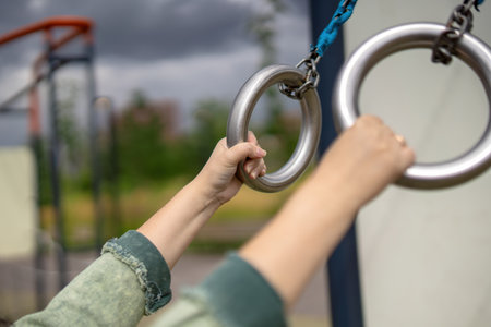 woman's hands grasp metal gymnastic rings, symbolizing strength, dedication, and the pursuit of...