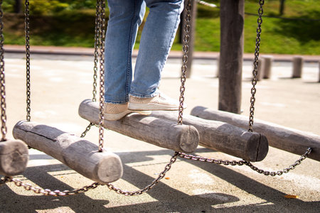 person navigates a challenging fitness apparatus: swinging logs suspended by metal chains, showcasing balance, strength, and determination in a dynamic outdoor training environmentの写真素材