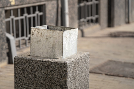 half-extended metal bucket inside a granite square bin evokes thoughts on waste and sustainability, reflecting society's ongoing struggle with consumption and environmental responsibilityの写真素材