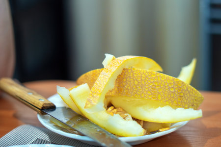 remnants of a ripe melon, its vibrant skin now a discarded shell, lie on a plate beside a knife, echoing the fleeting moments of indulgence and natures bountyの写真素材