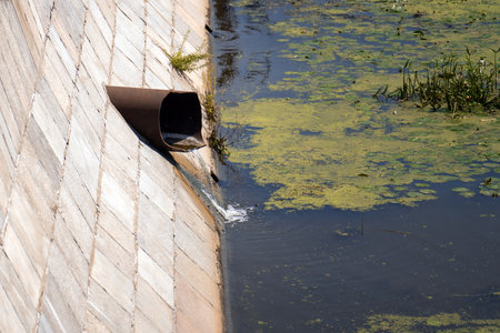 industrial waste flowing from a broken cast iron pipe into a river, symbolizing environmental degradation and the urgent need for pollution awareness and sustainabilityの写真素材