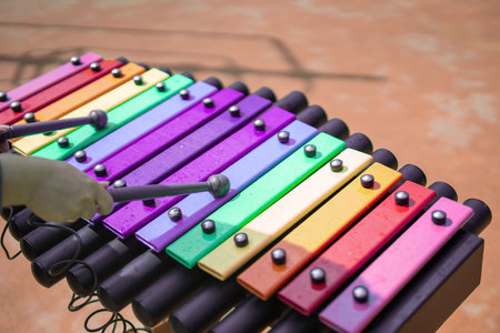 vibrant park scene, children gather around a public xylophone, creating joyful melodies together. The colorful instrument fosters creativity, community, and musical exploration under the sunの写真素材