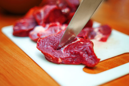 vibrant red piece of beef rests on a wooden table, showing the rich marbling and freshness of the meat. A polished chef's knife lies beside it, ready for preparation, embodied culinary artistryの写真素材