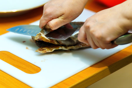 sharp knife delicately slices through a fish's fin, illustrating the art of culinary preparation. This moment captures the intersection of nature and gastronomic creativity, honoring traditionの写真素材