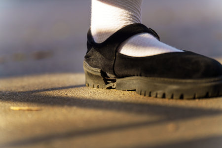 stark contrast of elegance and wear, a white sock-clad foot nestles in a black shoe, showcasing a fractured sole an emblem of fragility beneath a facade of sophisticationの写真素材