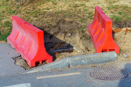 vibrant red plastic barrier surrounds a deep excavation for a well, symbolizing both the potential for life-giving water and the hidden dangers of neglecting safetyの写真素材
