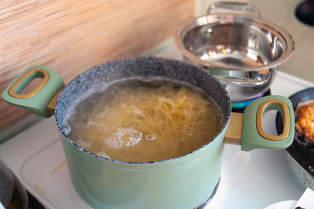simmering pot of spaghetti blissfully bubbles on an electric stove, embodying the essence of comfort food. This scene captures the warmth of home-cooked meals and culinary creativity.の写真素材