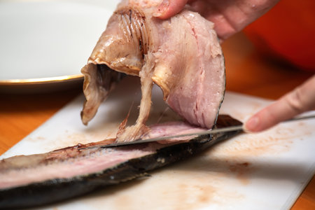 graceful process of filling red fish along the spine, highlighting culinary skill and the art of seafood preparationの写真素材