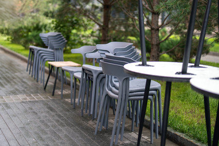 stack of colorful outdoor furniture, neatly arranged on the sidewalk outside a restaurant,...