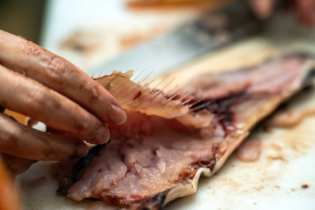 close-up of womens hands skillfully preparing fish, carefully filling it. The image captures the...