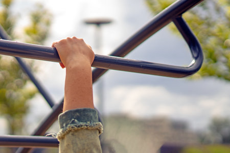 human hand gripping a metallic horizontal bar, symbolizing strength, perseverance, and the challenge of overcoming obstacles in physical fitnessの写真素材