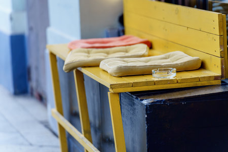 cozy scene featuring a makeshift wooden bench on a windowsill, adorned with inviting cushions and accompanied by a delicate glass ashtray. A perfect spot for relaxation and contemplationの写真素材