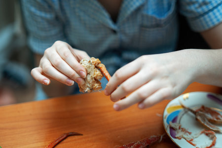 teenager's hand holding pieces of cooked crab, showing the delicious seafood delicacy. Perfect for food blogs, culinary articles, and seafood promotionsの写真素材