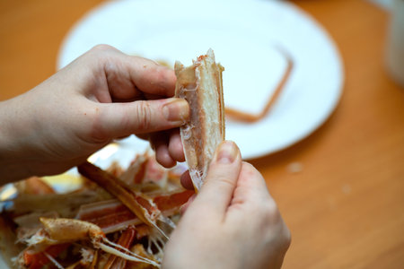hand reaches into a segment of a boiled crab, pulling out a large piece of succulent crab meat, showcasing the delicious seafood delicacyの写真素材