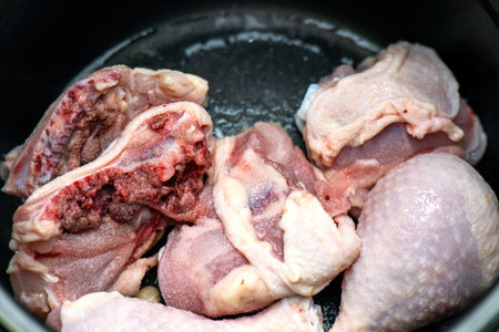 Fresh chicken drumsticks sprinkled with salt, resting in a cooking pot, ready for seasoning and preparation. Ideal for culinary and food photographyの写真素材