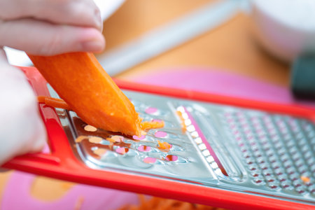 freshly grated peeled carrots on a large grater. Bright orange shreds create a vibrant, healthy ingredient perfect for salads, soups, and other dishesの写真素材