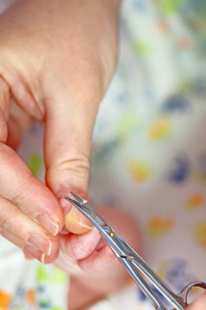 woman hand using thin metal scissors trim child nails on a small hand, showcasing care and attention to grooming.の写真素材